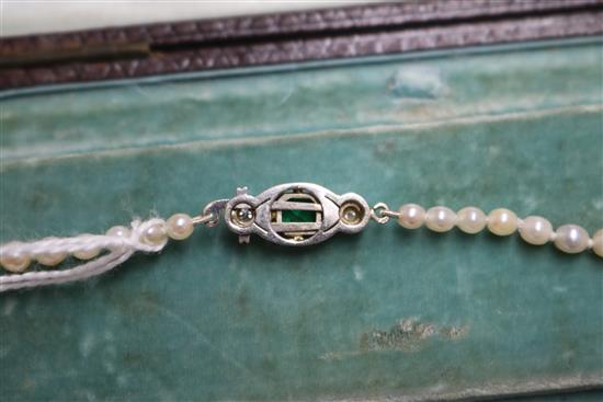 A single strand graduated cultured pearl necklace with an emerald and diamond set white metal clasp, approx. 35cm.